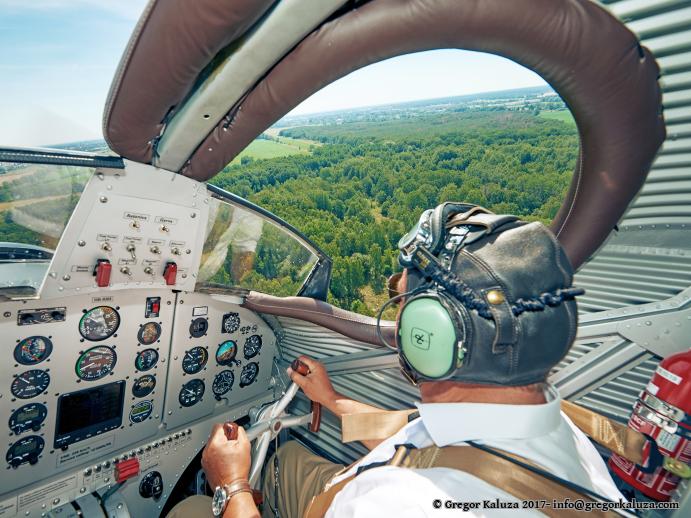 Der Co-Pilot am Steuerknüppel im offenen Cockpit der „JUNKERS F13“. Durch ein kleines Fenster können die Passagiere ihm über die Schulter blicken. Sie sitzen in einer geschlossenen Kabine, während den beiden Flugzeugführern der Wind um die Nase weht. Aufgenommen in Dessau (Sachsen-Anhalt) im Juni 2019 © VJL / Foto: Gregor Kaluza / Junkers Flugzeugwerke AG